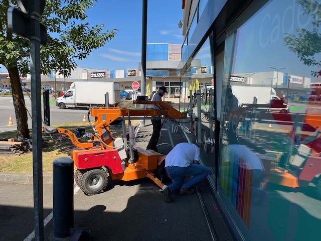 Technicien mettant en place une vitre avec une machine orange